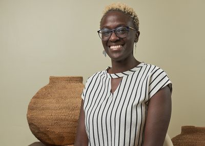 Tolu Ilelaboye, volunteer project manager with African Communities of Manitoba Inc. sits in front of a large woven basket.